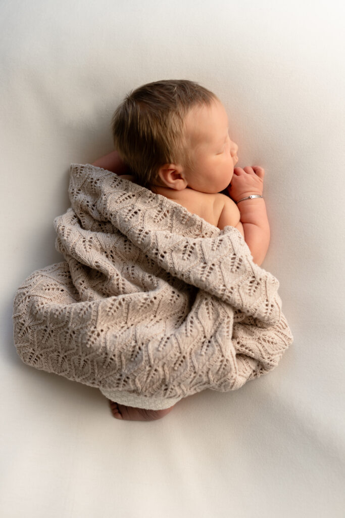 Foto van bovenaf newborn met dekentje over zich heen op de beanbag