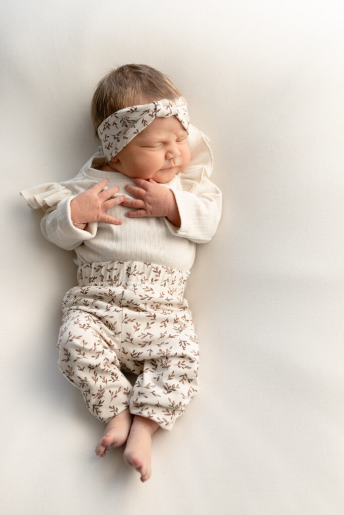 bovenaanzicht van newborn met kleertjes aan handjes op de borst