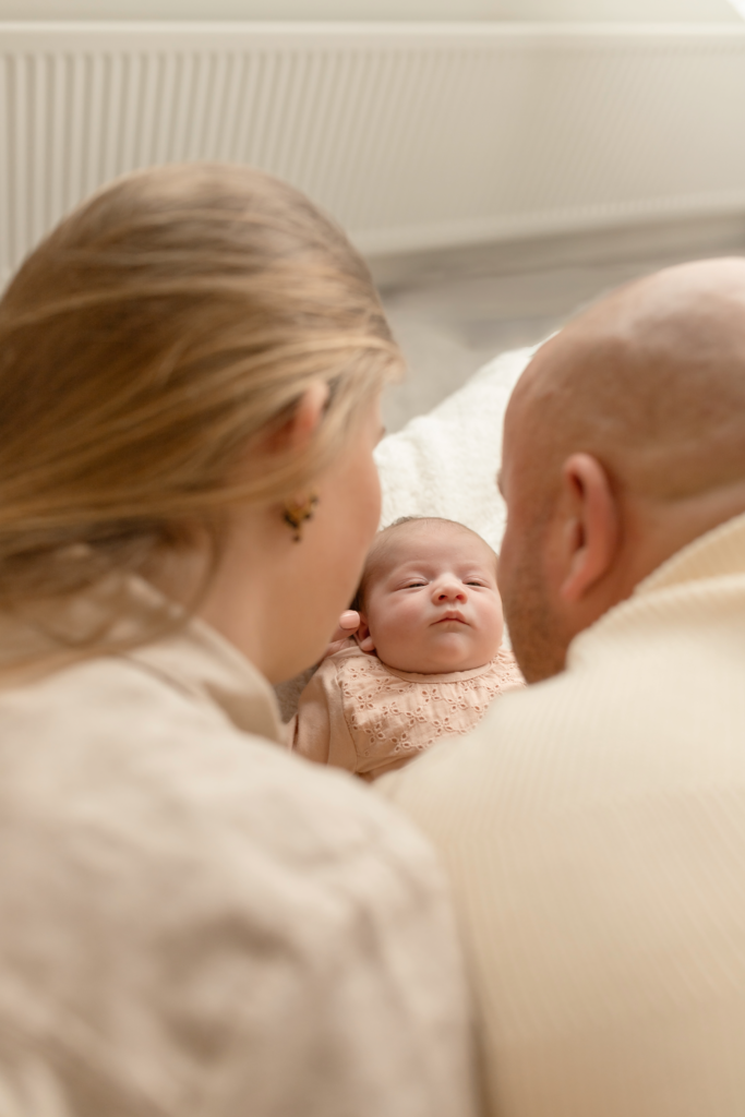 newborn foto van het gezicht van het kindje tussen papa en mama door gezien