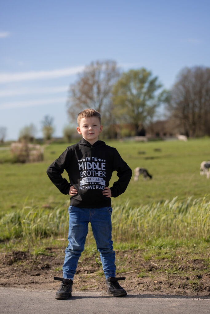 de middelste zoon alleen op de foto met schapen op de achtergrond
