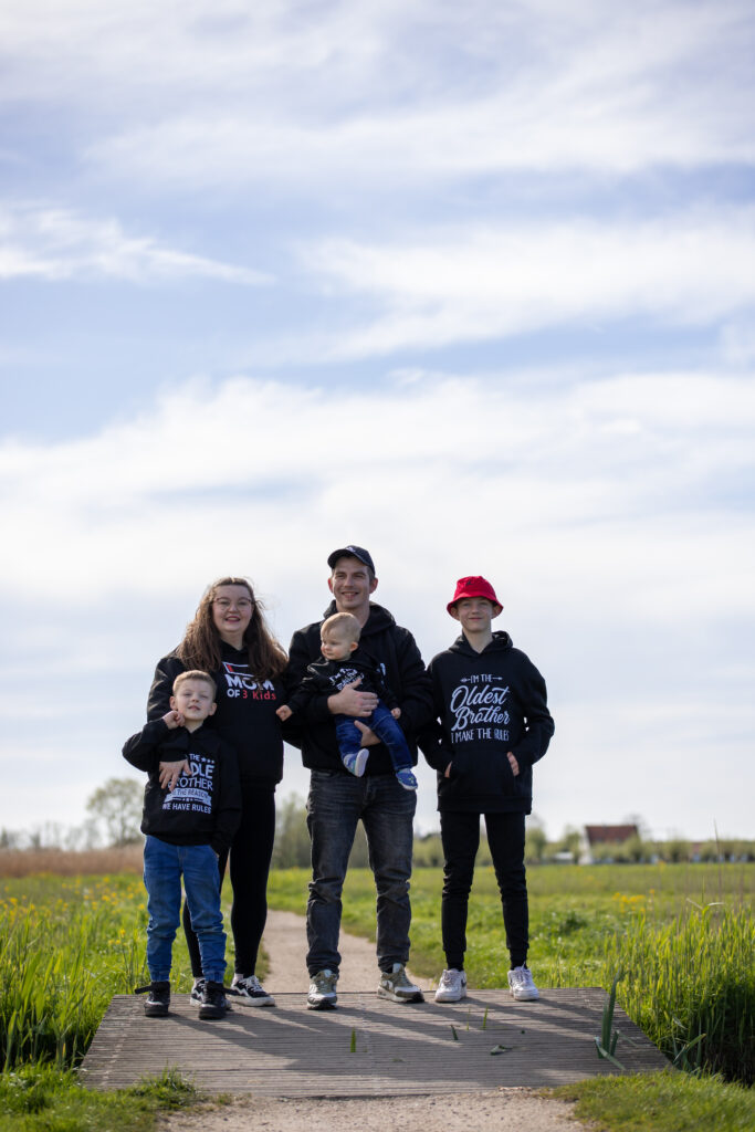 Het hele gezin staat op de foto met een zwarte trui aan op een zonnige dag in mei