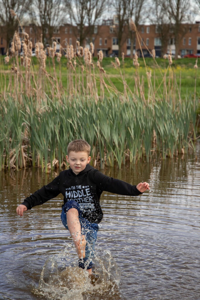 De middelste zoon staat alleen op de foto en stampt met zijn voeten in het water