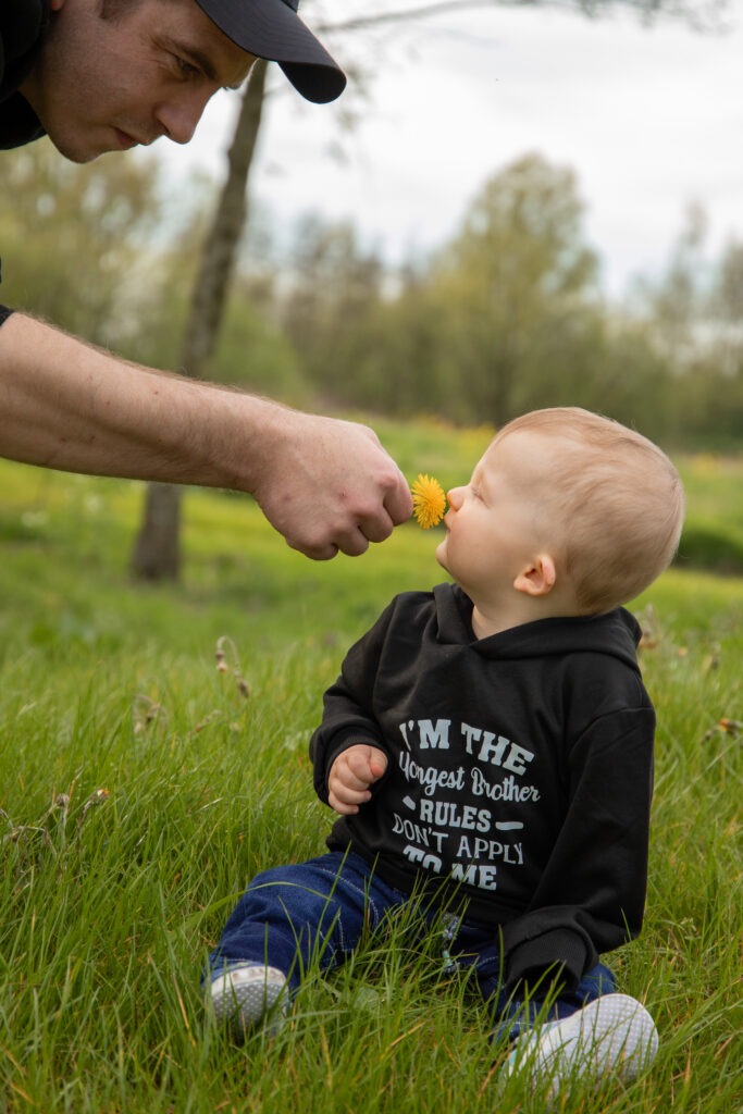 vader laat jongste zoon ruiken aan een paardenbloem