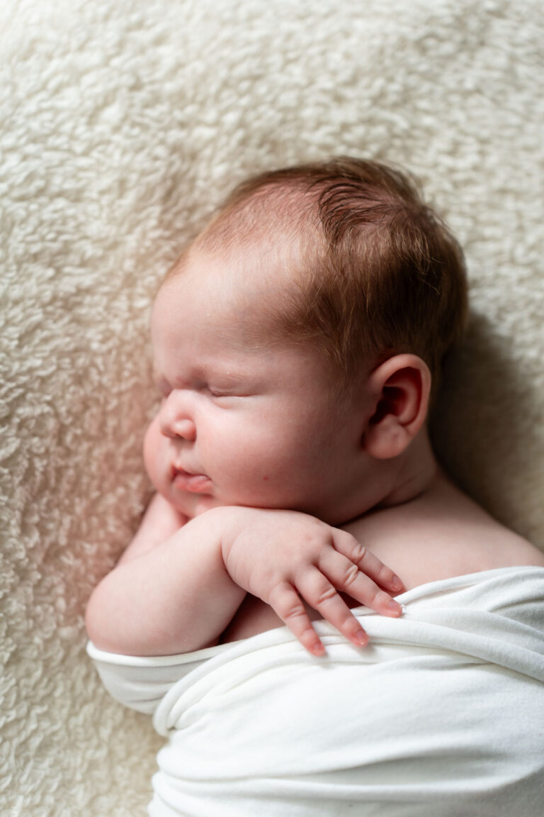 Slapende pasgeboren baby op een zacht kleed, vastgelegd door newborn fotograaf in Spijkenisse