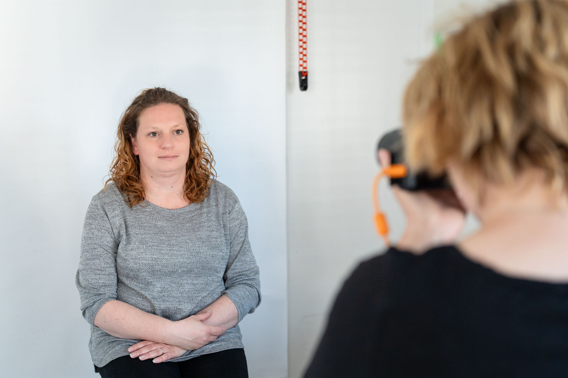 Daphne maakt een pasfoto van een klant in haar studio, volgens de officiële richtlijnen en met een rustige benadering.