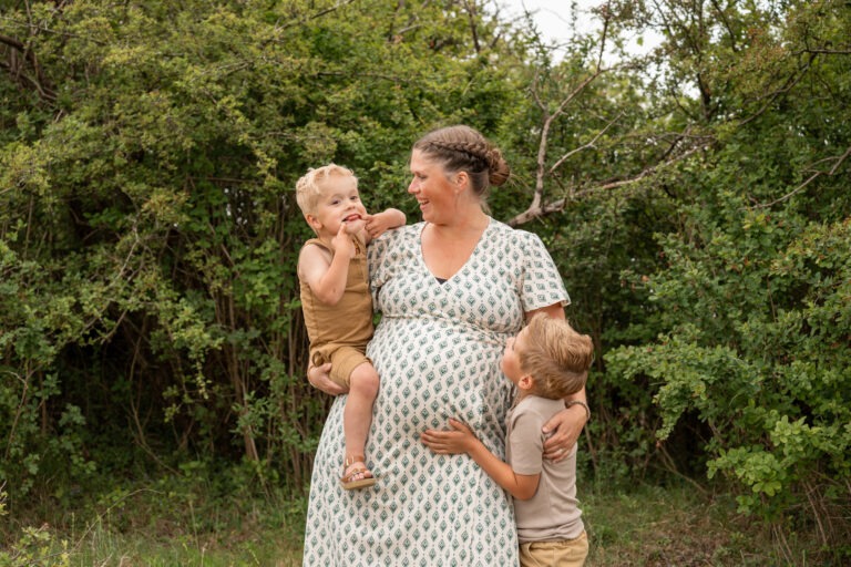 Zwangerschapsshoot met moeder en zoon, warme omhelzing in de natuur