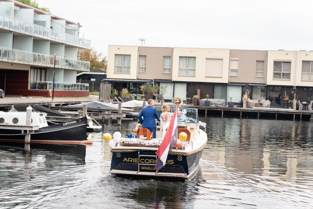 Bruidspaar vaart weg richting de trouwlocatie De boot met witte en gouden ballonnen vaart langzaam weg over het water, terwijl het bruidspaar richting de ceremonie vertrekt.