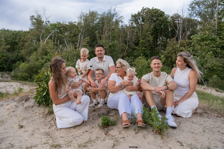 Grote familiefoto in de duinen van Rockanje Drie generaties bij elkaar tijdens een familieshoot in Rockanje – zittend in het zand, omringd door groen en gekleed in neutrale tinten. Een warme en vrolijke groepsfoto vol echte momenten.