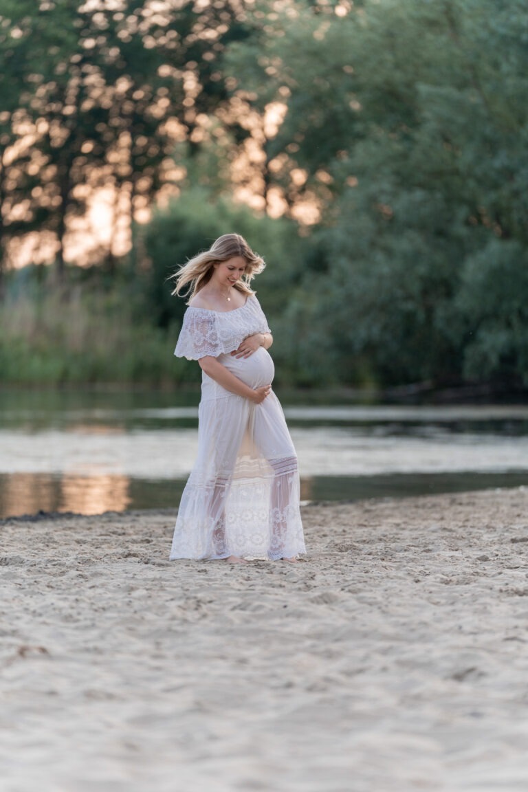Zwangere vrouw in witte jurk uit de client closet, gefotografeerd in de Bernisse
