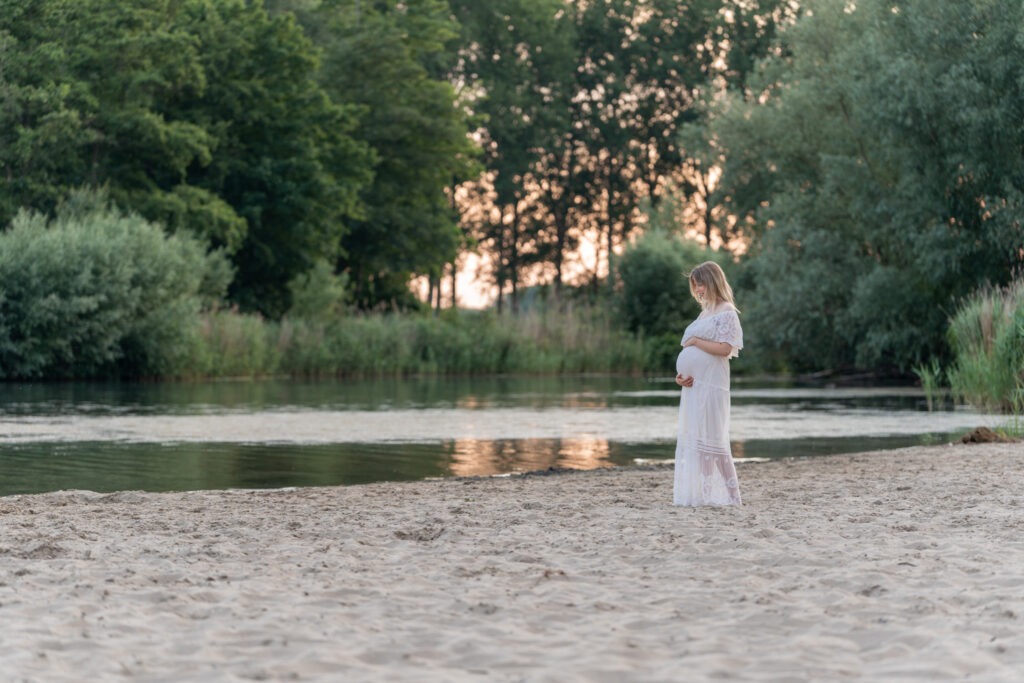 Zwangere vrouw kijkt liefdevol naar haar buik tijdens fotoshoot in de Bernisse