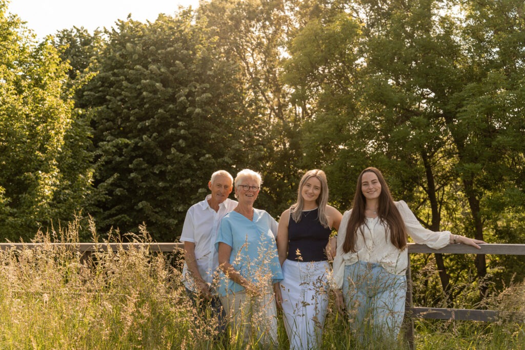 Familie poseert samen tussen het hoge gras met warm zonlicht op de achtergrond tijdens een familie fotoshoot Brielle.