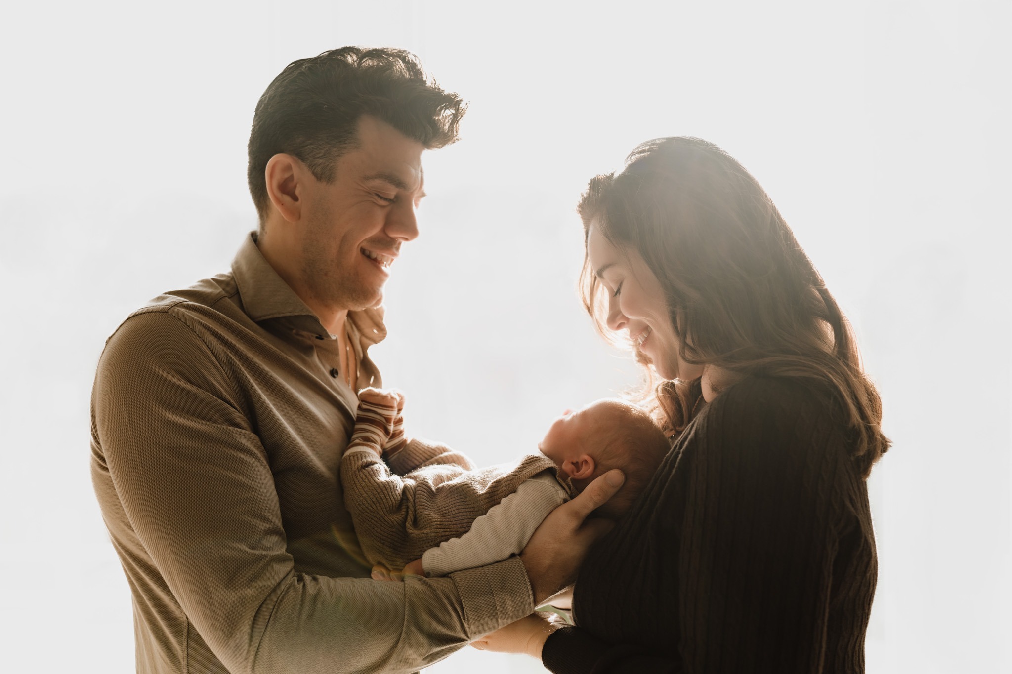 Baby Tommie slapend vastgehouden tijdens de newbornshoot bij hem thuis in Zuidland, een warm en intiem moment vastgelegd door Daphne's Fotografie