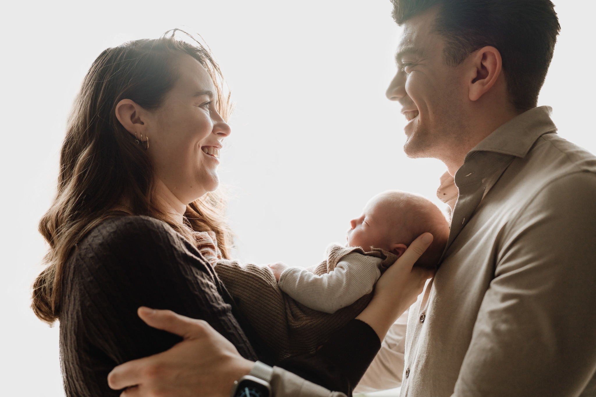 Ouder houdt baby Tommie dicht tijdens de newbornshoot in Zuidland, zacht daglicht en een liefdevolle sfeer