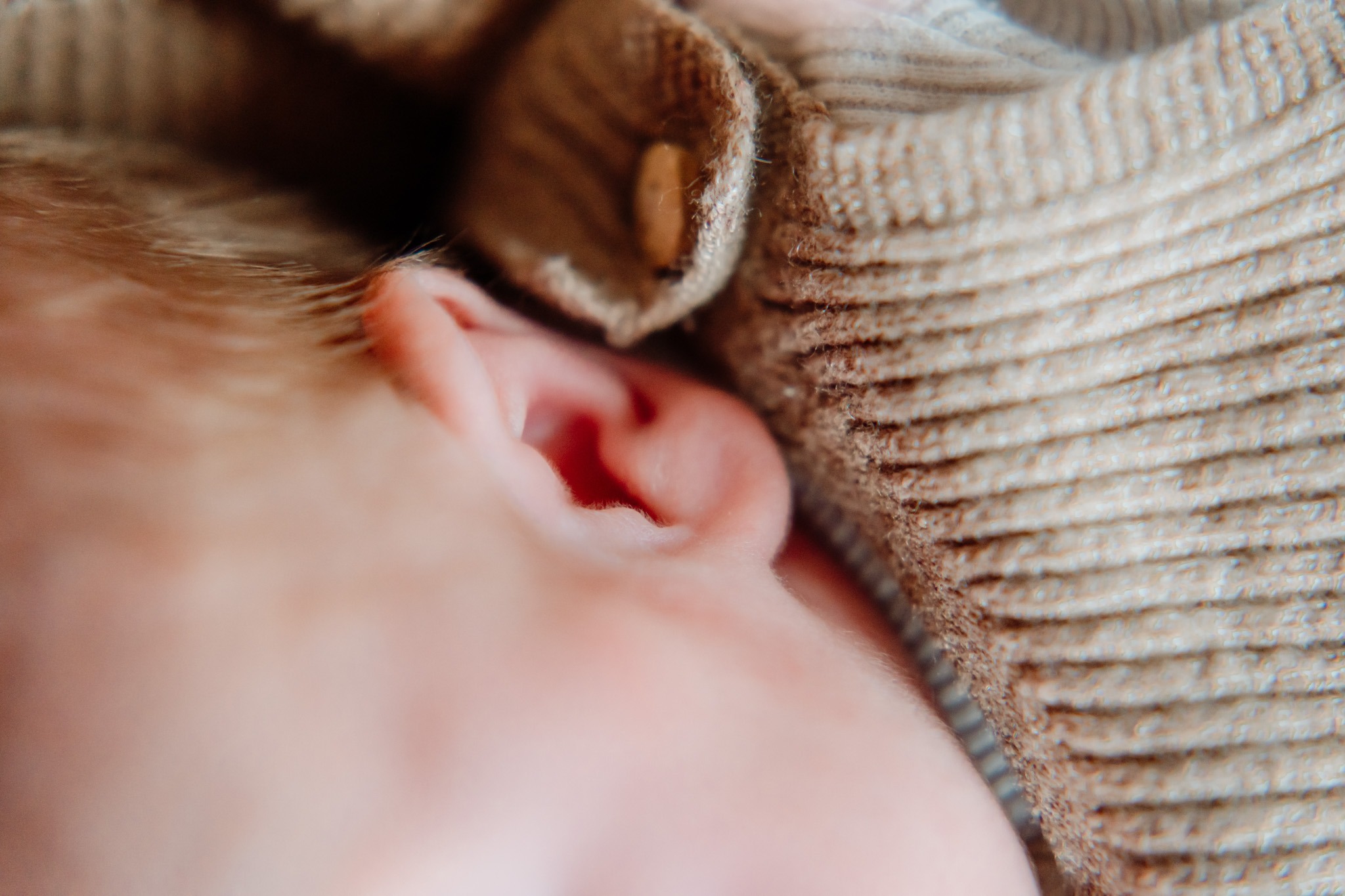 Baby Tommie in de armen van zijn ouders tijdens de newbornshoot thuis in Zuidland, een tijdloos en liefdevol beeld