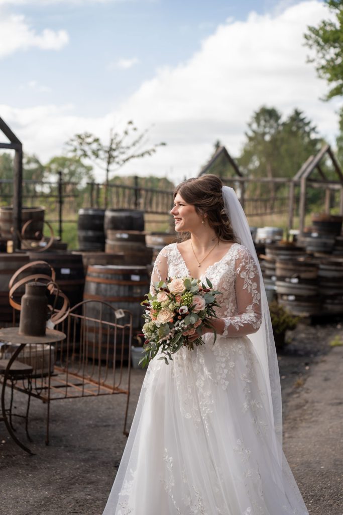 Bruid loopt lachend met haar bruidsboeket door een industriële trouwsetting