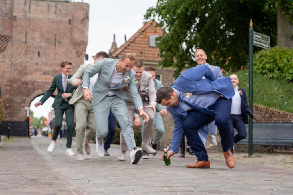 Vriendengroep van de bruidegom springt en lacht tijdens een speels moment op de bruiloft