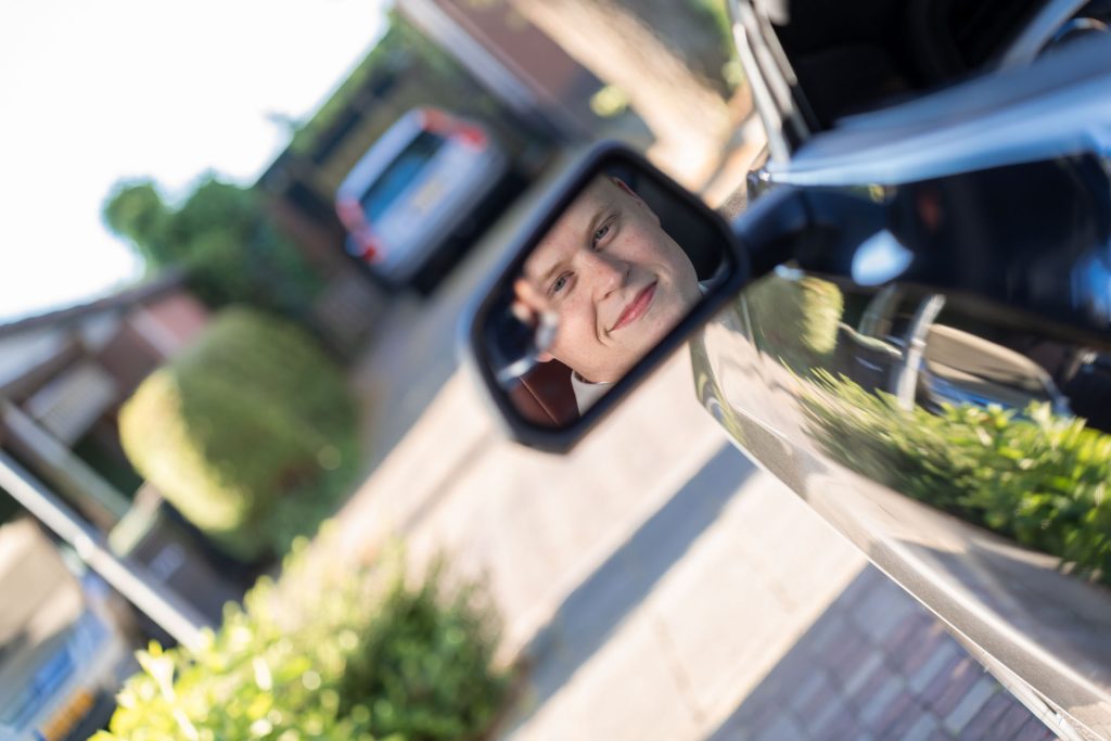 Reflectie van de bruid in de spiegel van een auto tijdens het moment voor de ceremonie