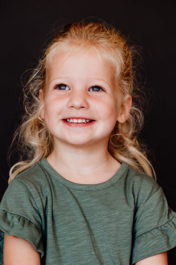 Spontane lach van een meisje van bijna drie jaar tijdens een portretfoto in Zuidland in de studio.