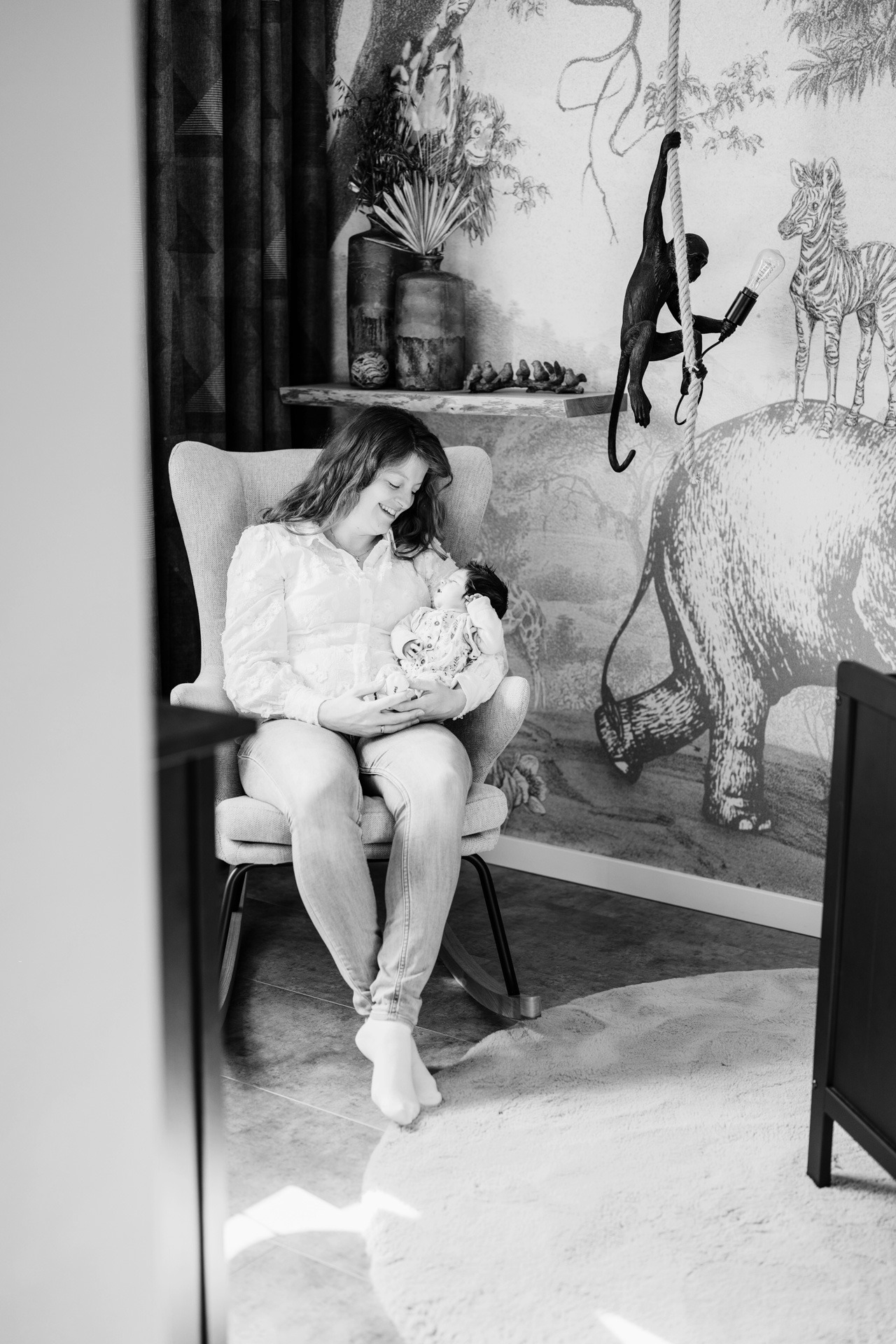 Moeder zit ontspannen met haar pasgeboren baby in huiselijke setting tijdens een zwangerschap newbornshoot