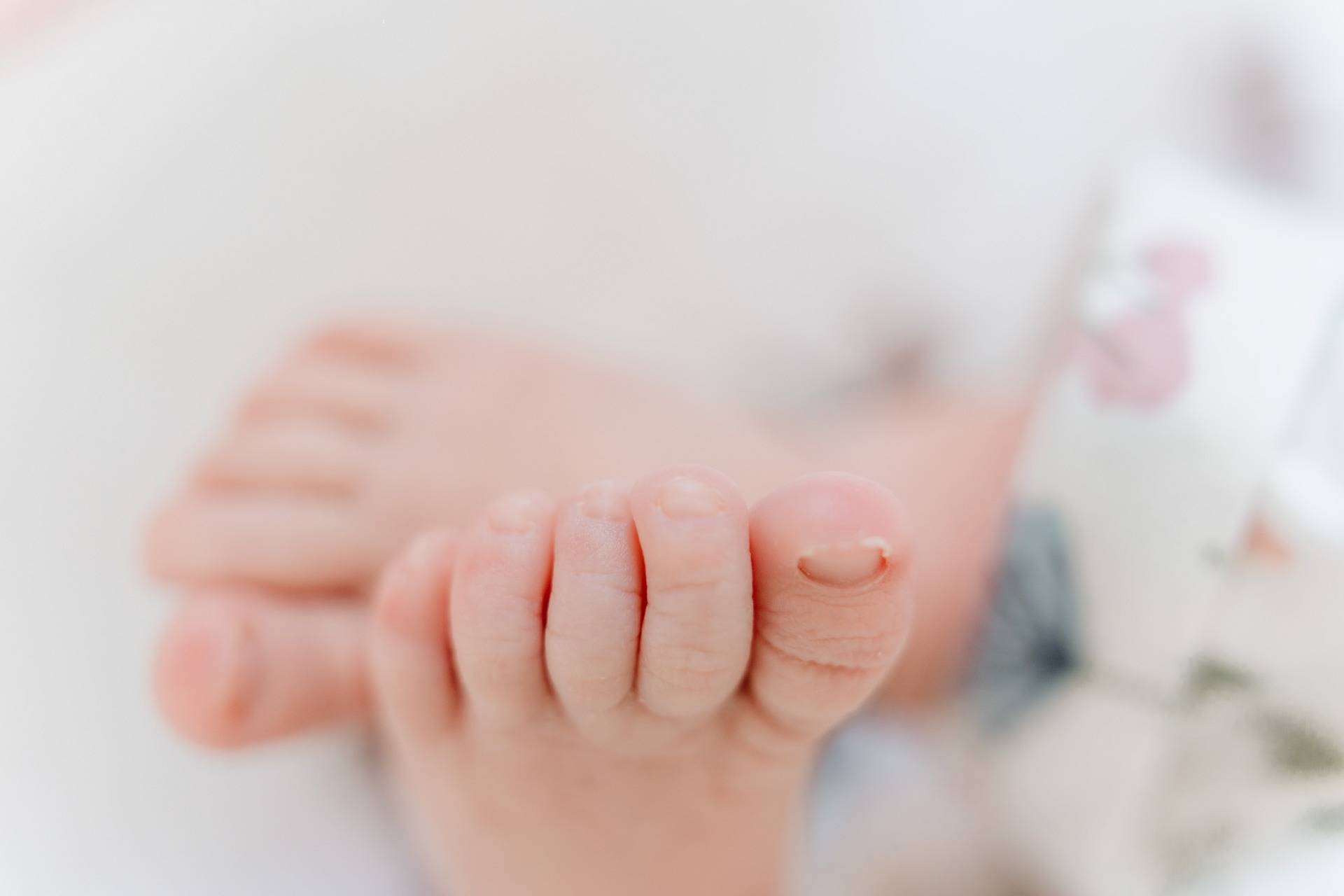 Close-up van kleine babyvoetjes tijdens een zwangerschap newbornshoot met zachte en lichte kleuren