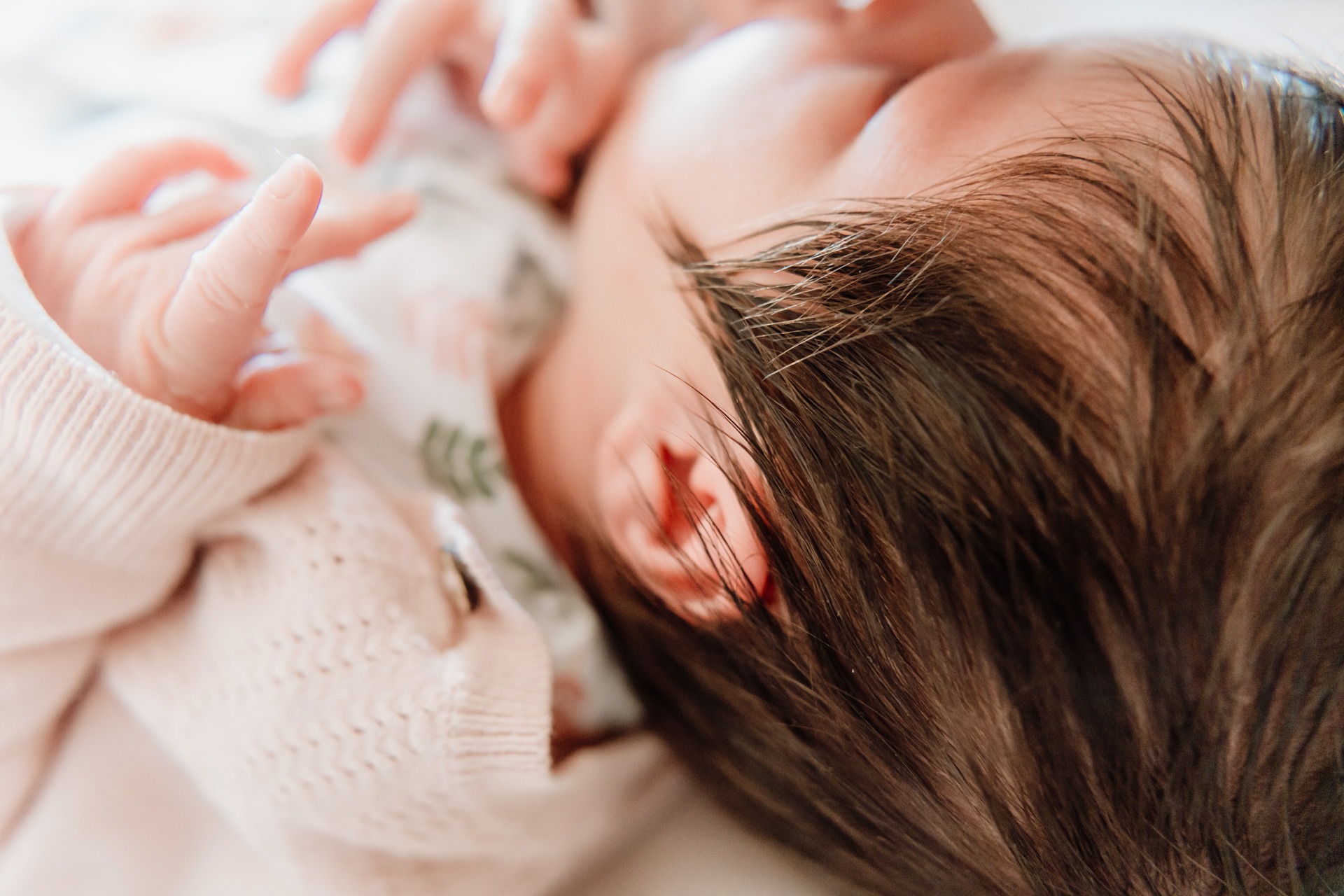 Detail van pasgeboren baby met zacht haar en kleine hand tijdens een zwangerschap newbornshoot