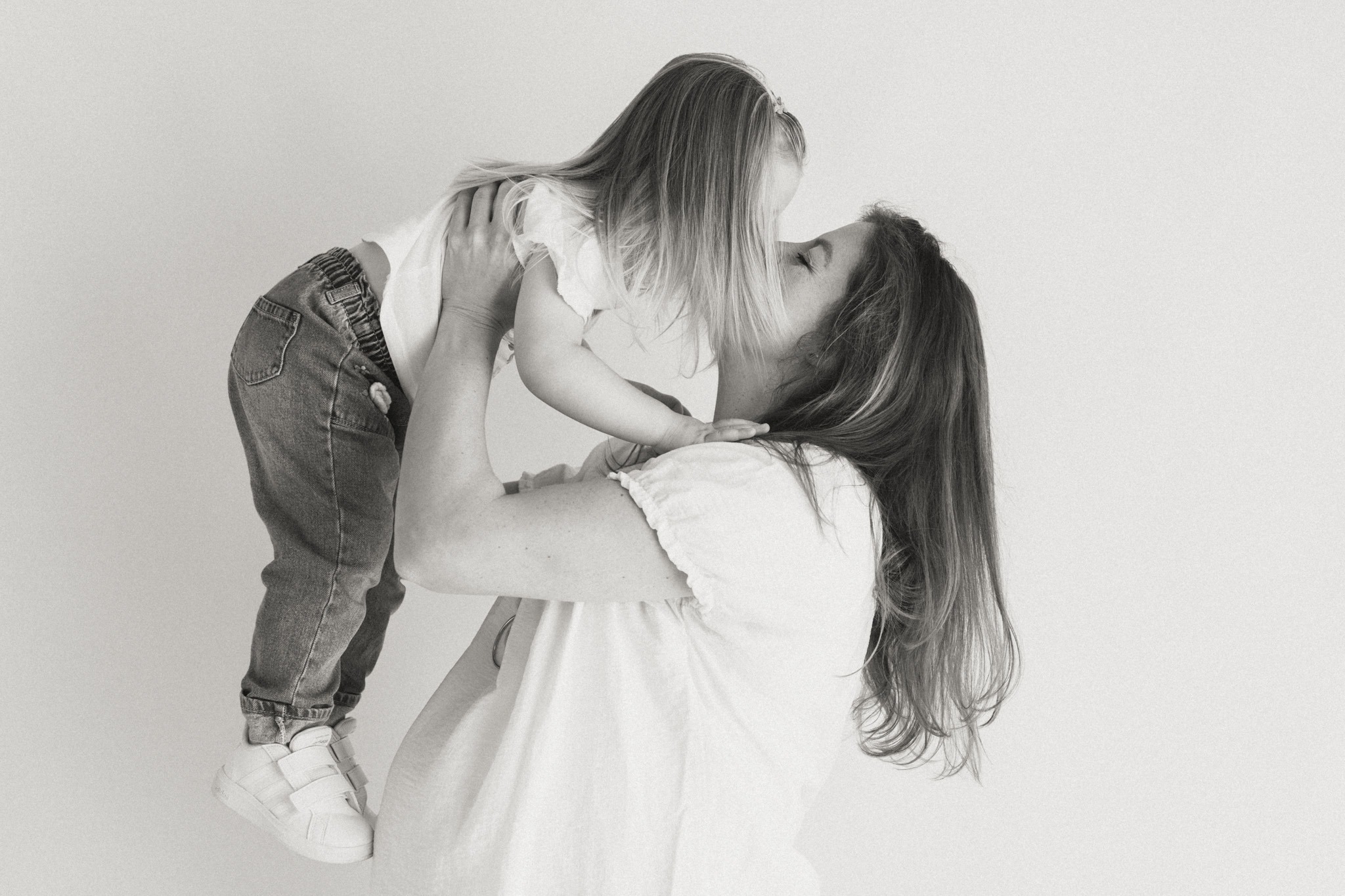 Moeder tilt haar baby omhoog tijdens een liefdevolle zwangerschap newbornshoot met focus op verbinding