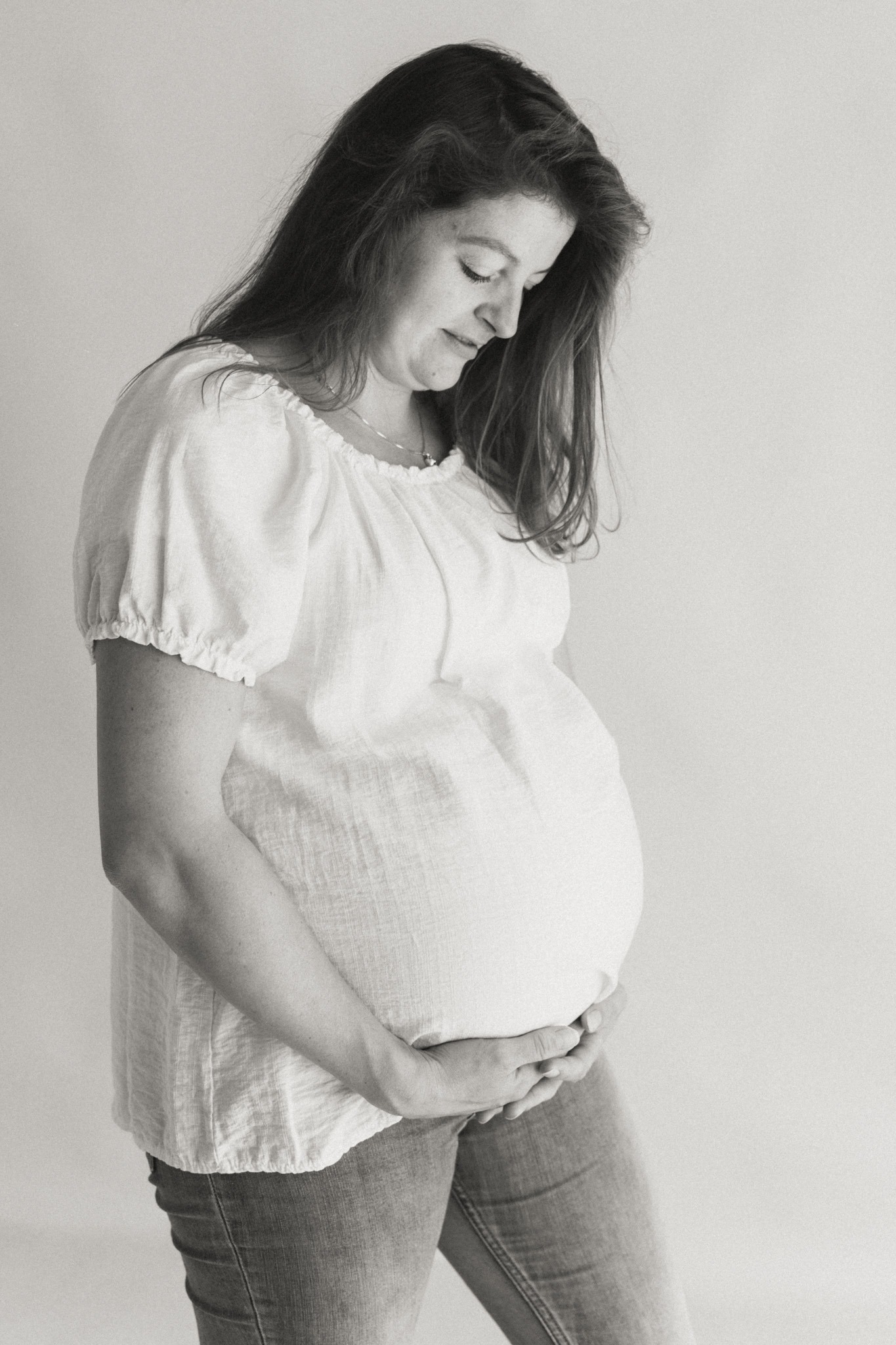 Zwart-wit portret van zwangere vrouw met handen op buik tijdens een zwangerschap newbornshoot