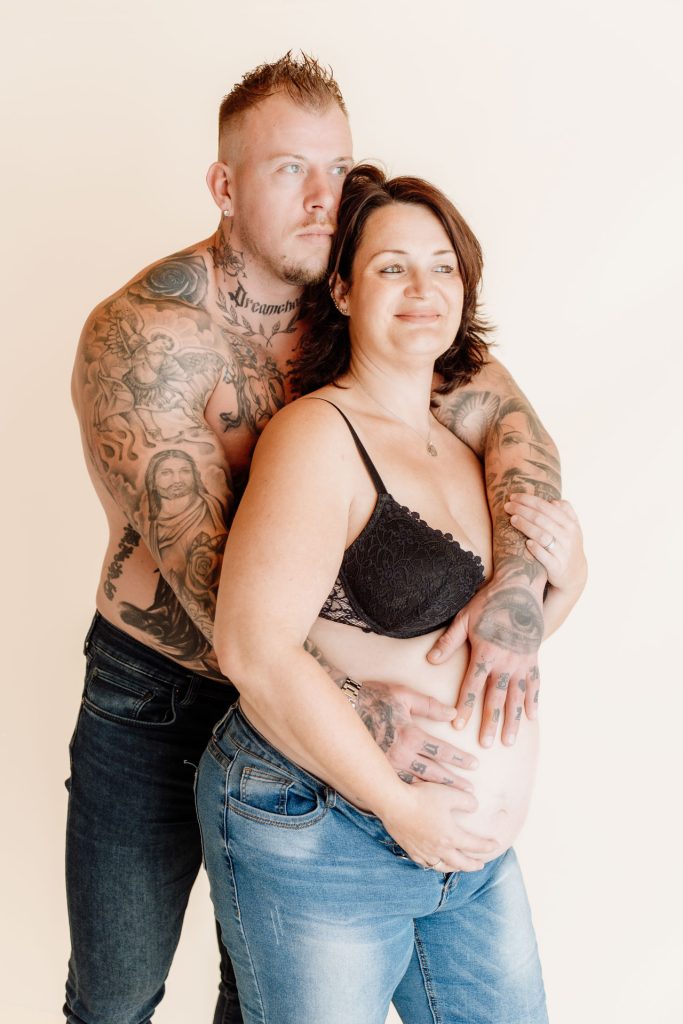 Sanne en Mike tijdens de zwangerschapsshoot in de studio in Zuidland, Mike staat achter Sanne en houdt liefdevol haar zwangere buik vast