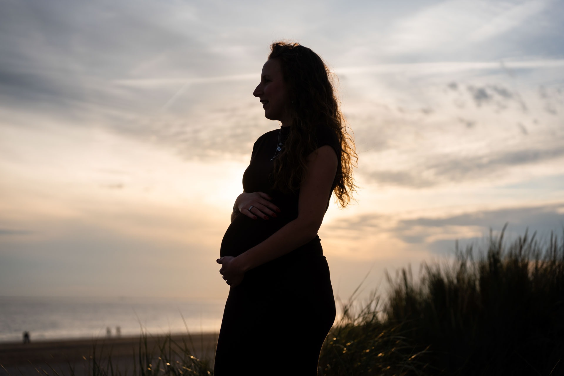 Silhouet van zwangere vrouw tegen de zonsondergang op het strand van Rockanje