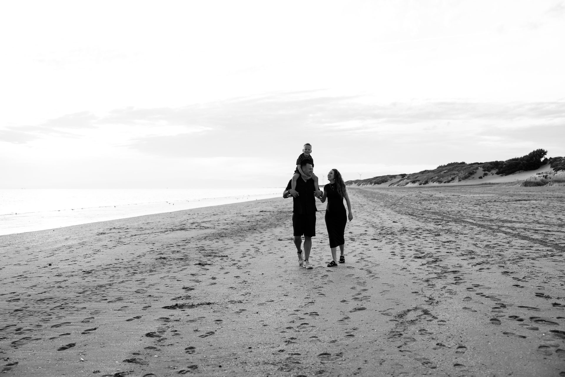 Gezin wandelt over het strand van Rockanje met zoontje op papa's schouders