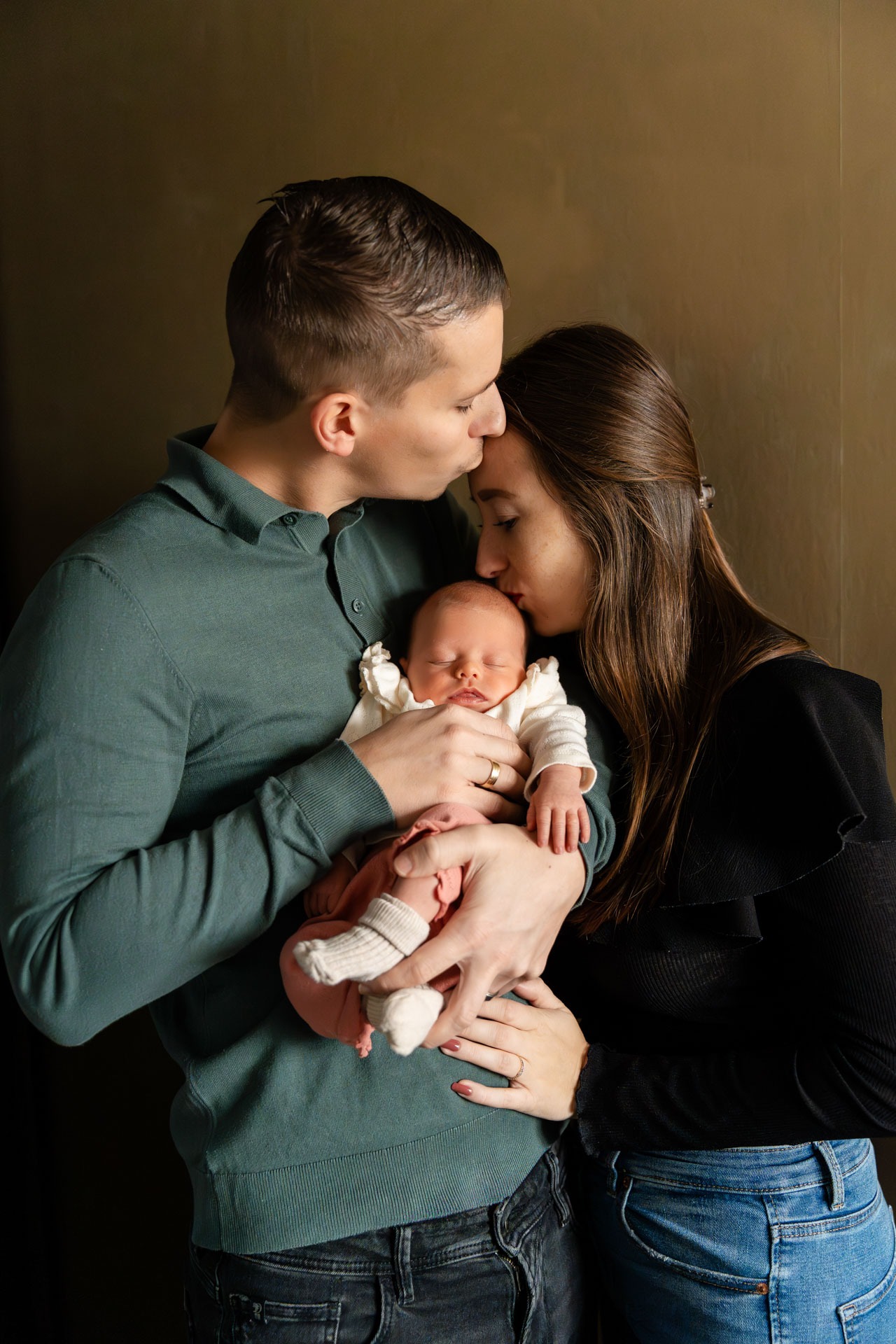 Newborn fotoshoot in Zuidland, papa en mama kussen hun baby