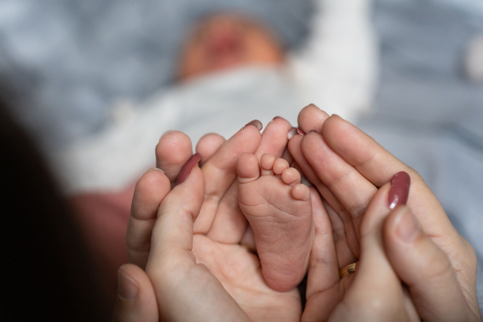 Newborn fotoshoot in Zuidland, detail babyvoetje in handen van moeder