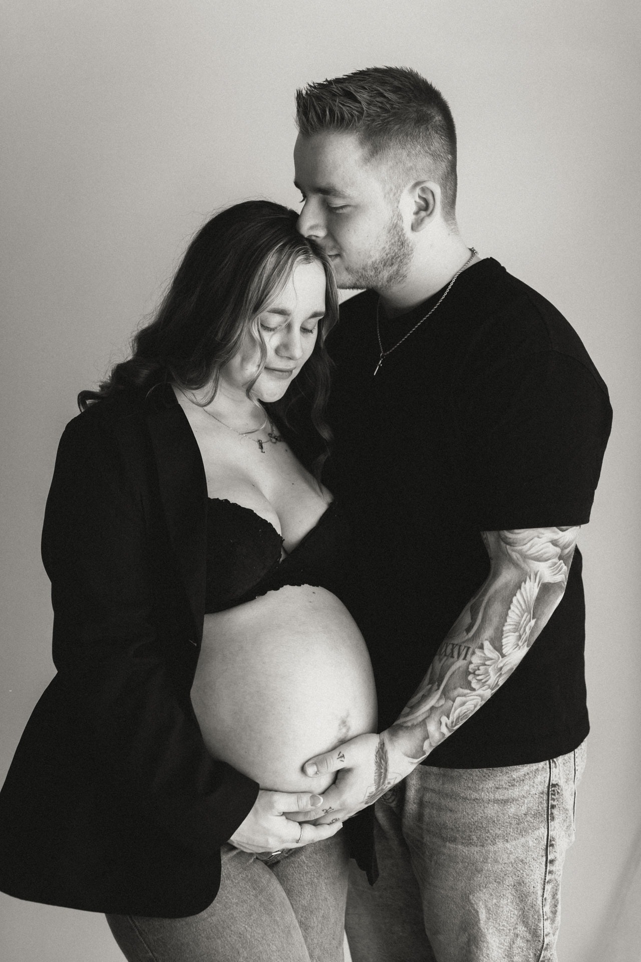 Zwart-witfoto van stel dat samen de babybuik vasthoudt tijdens zwangerschapsshoot in de studio