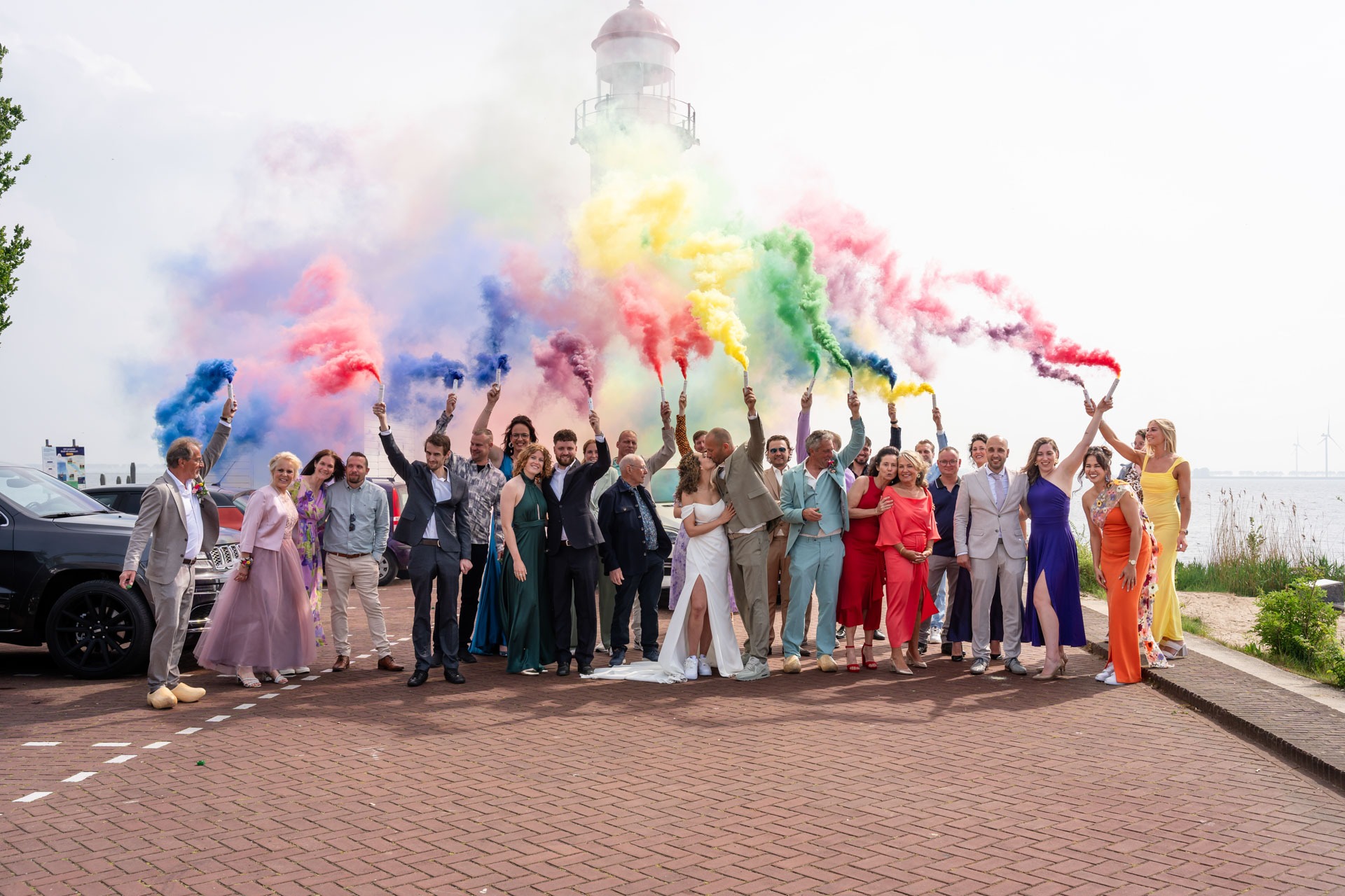 Groepsfoto met gekleurde rookfakkels voor de vuurtoren, vastgelegd door trouwfotograaf Hellevoetsluis