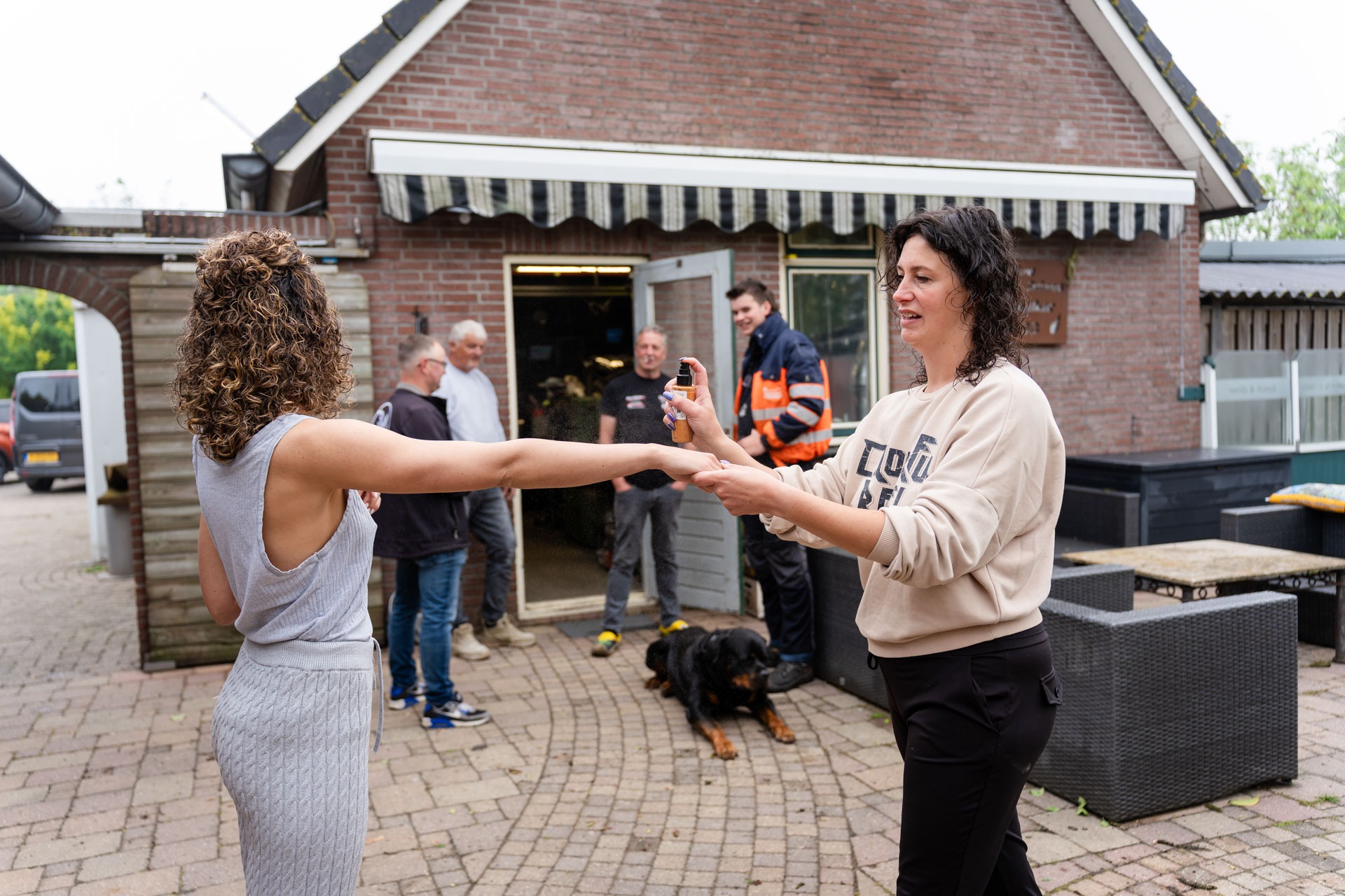 Bruid maakt zich klaar en wordt ingespoten met parfum, met hond op de achtergrond