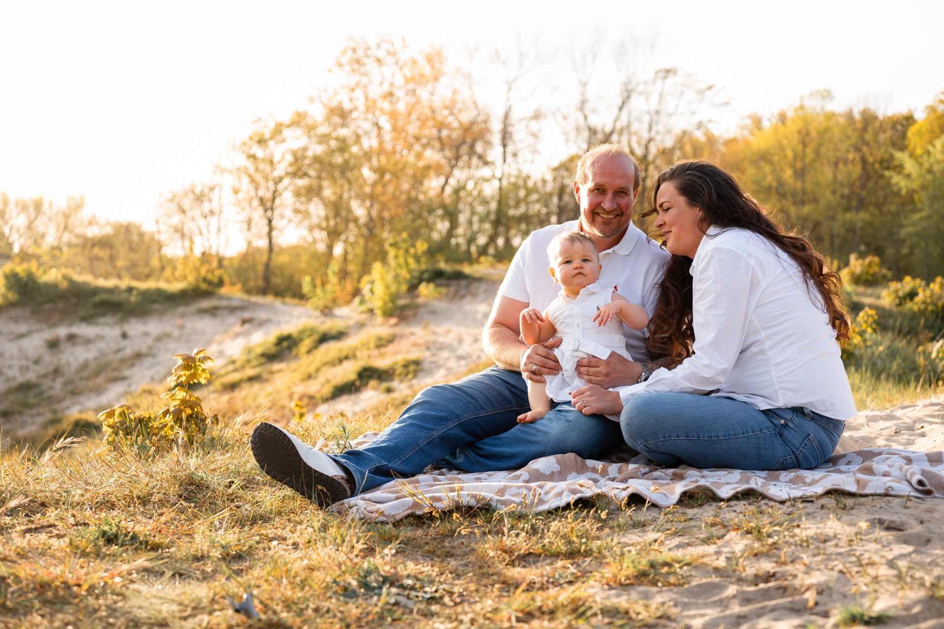 Vader, moeder en dochtertje samen op een kleedje in de duinen bij familieshoot strand Rockanje