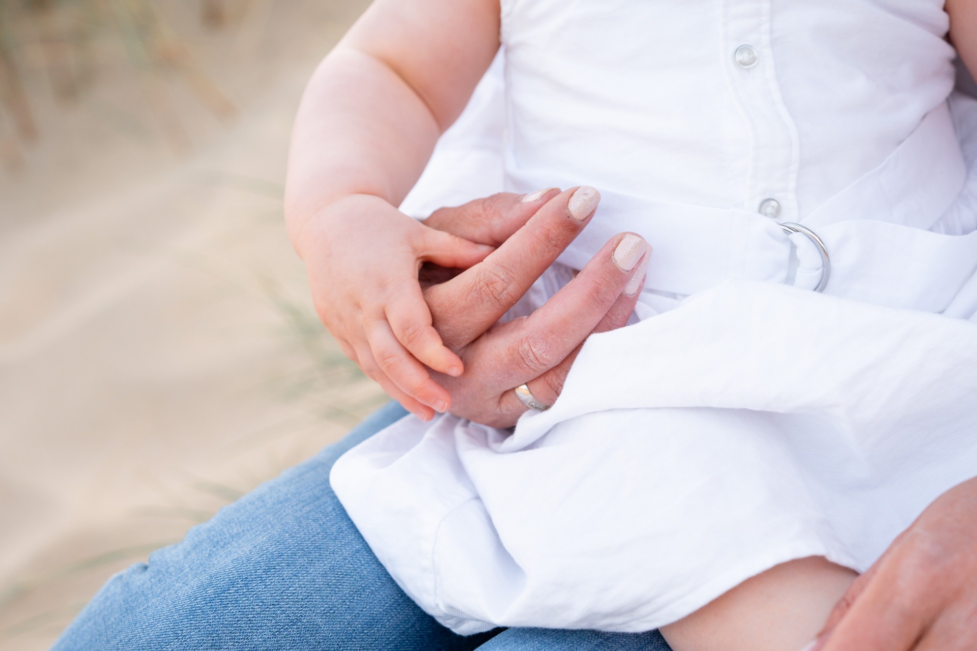 Klein babyhandje in de hand van mama tijdens familieshoot op het strand van Rockanje