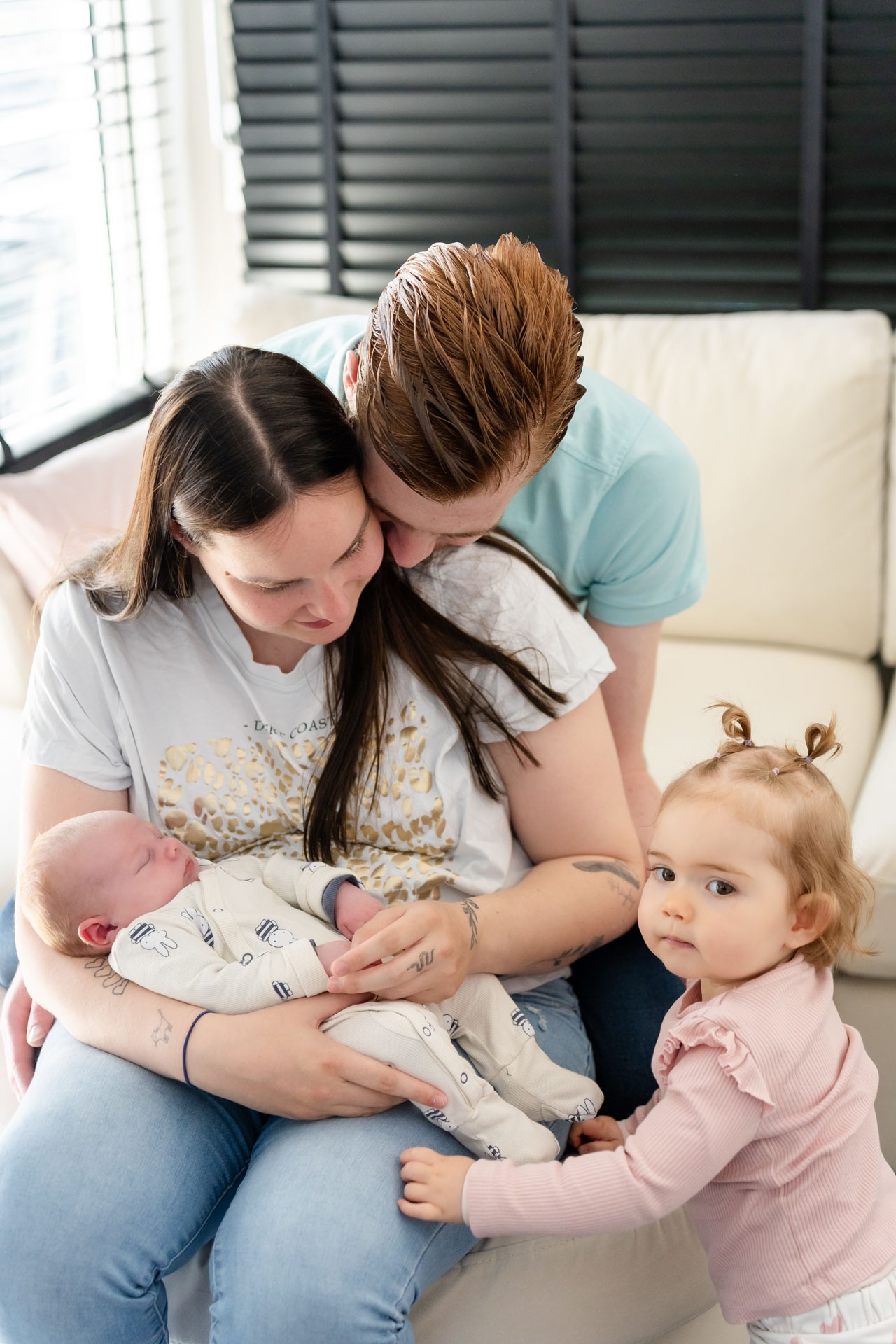 Gezin met pasgeboren baby en grote zus op de bank tijdens newbornshoot aan huis Zwartewaal