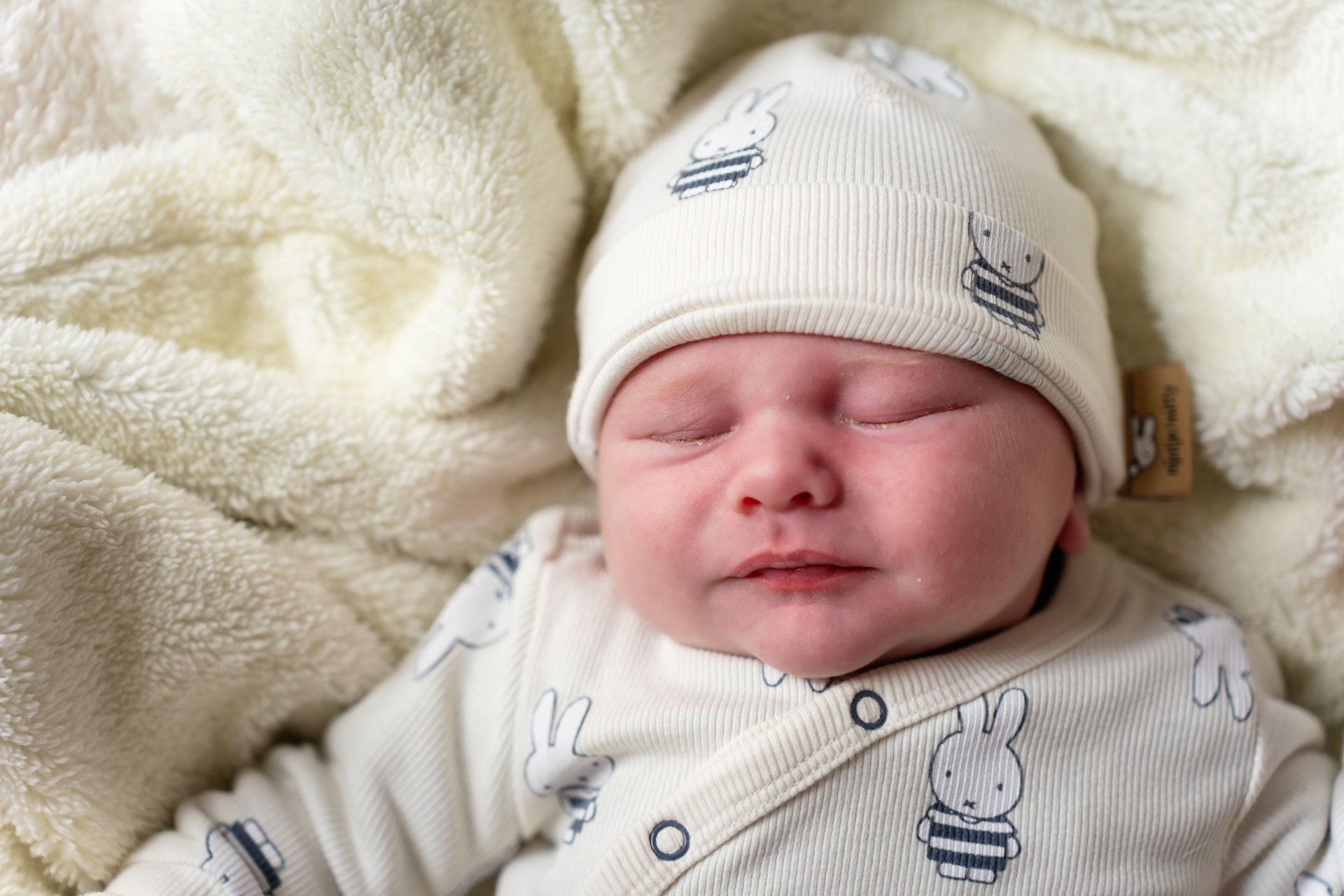 Slapende pasgeboren baby Jace in nijntje-pakje tijdens newbornshoot aan huis Zwartewaal