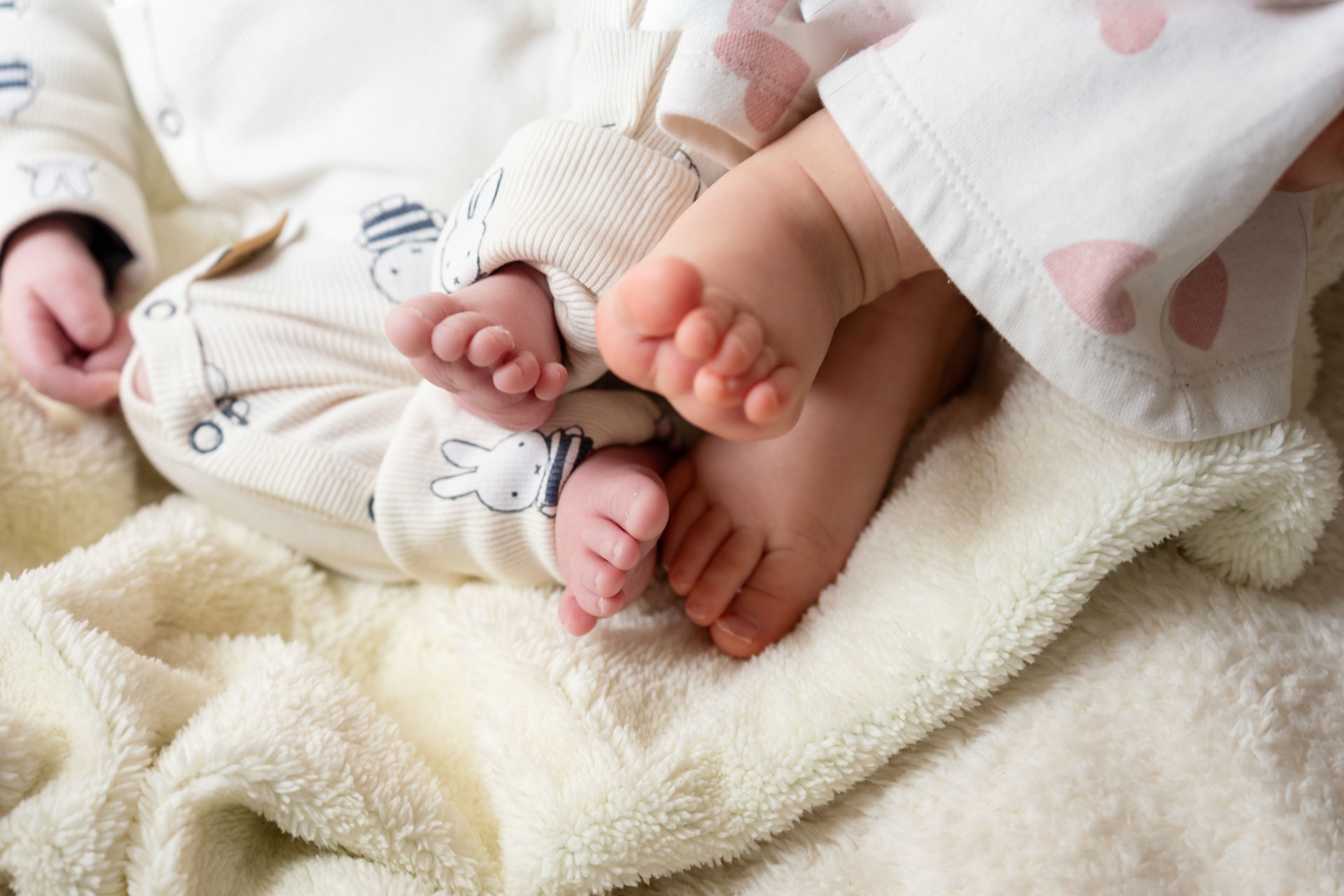 Voetjes van baby en grote zus samen tijdens newbornshoot aan huis