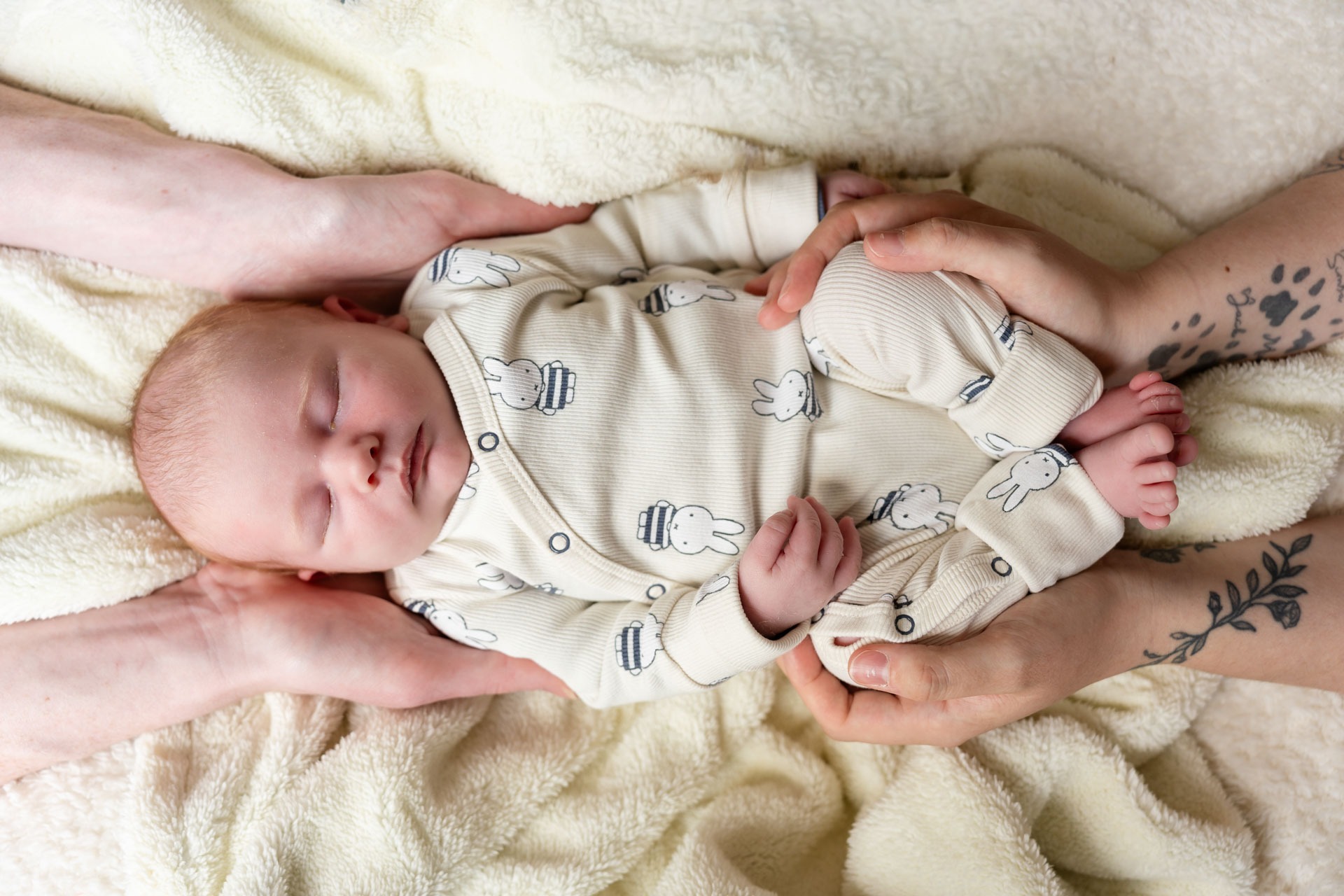 Ouderhanden om pasgeboren baby heen tijdens newbornshoot aan huis
