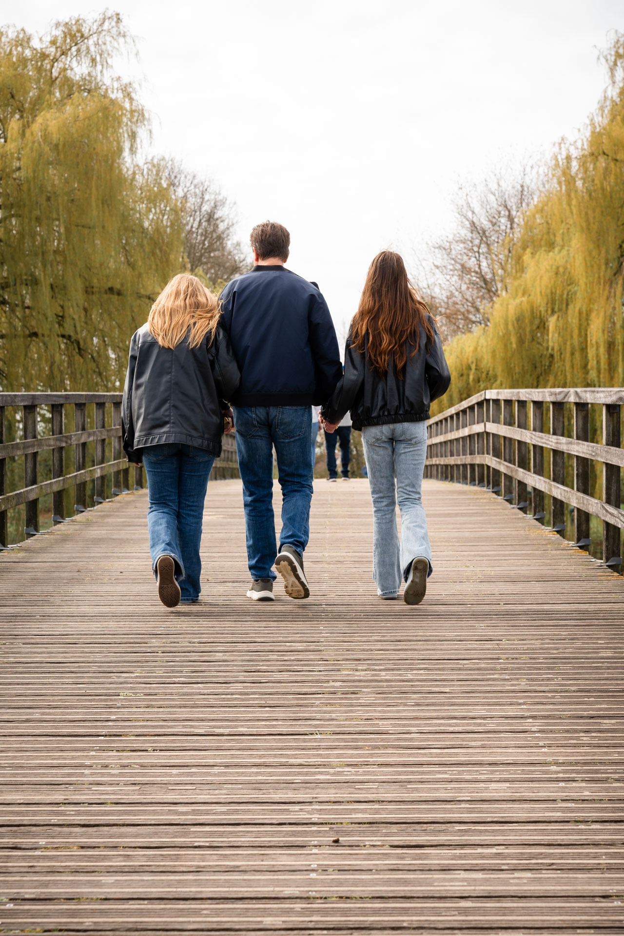 Familieleden wandelen samen over een bospad tijdens familieshoot in Abbenbroek