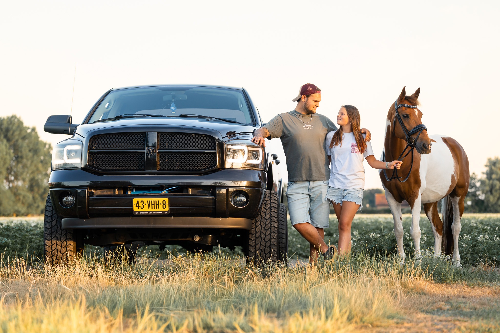 Zwarte pick-up met broer, zus en pony in het avondlicht in Tinte