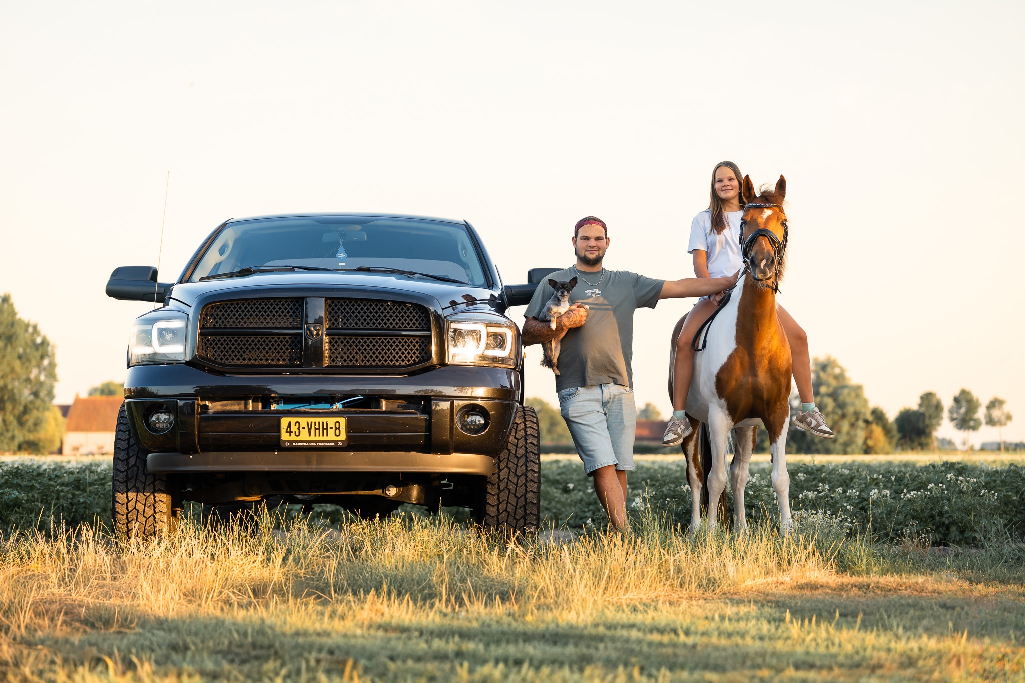 Broer en zus met de pony naast de stoere zwarte pick-up