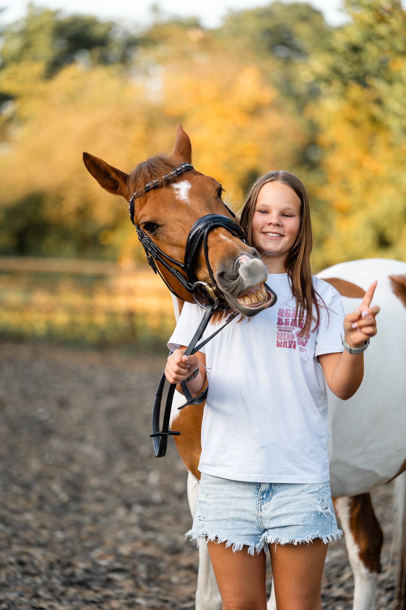Lachend meisje in wit shirt met haar bonte pony tijdens paardenshoot in Tinte